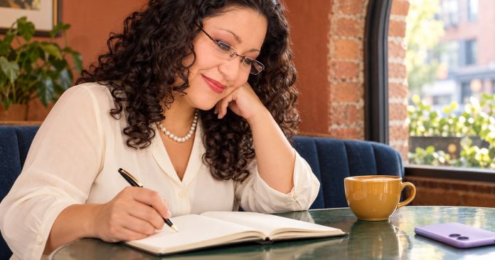 Reflecting on relationship patterns —352 Woman in rimless glasses writing in a notebook at a café table